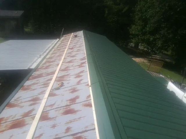 Old rusted panels beside newly installed green metal roofing — Wind Damage Roof Repair by Roofing Brothers in Woodville
