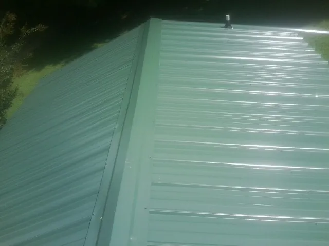 New green metal panels meeting at the ridge of a roof — Flat Roof Repair work by our crew in Woodville