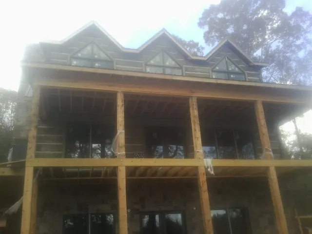 Dormers and porch framing on a large log home under construction — Roof Coating work by our crew in Woodville
